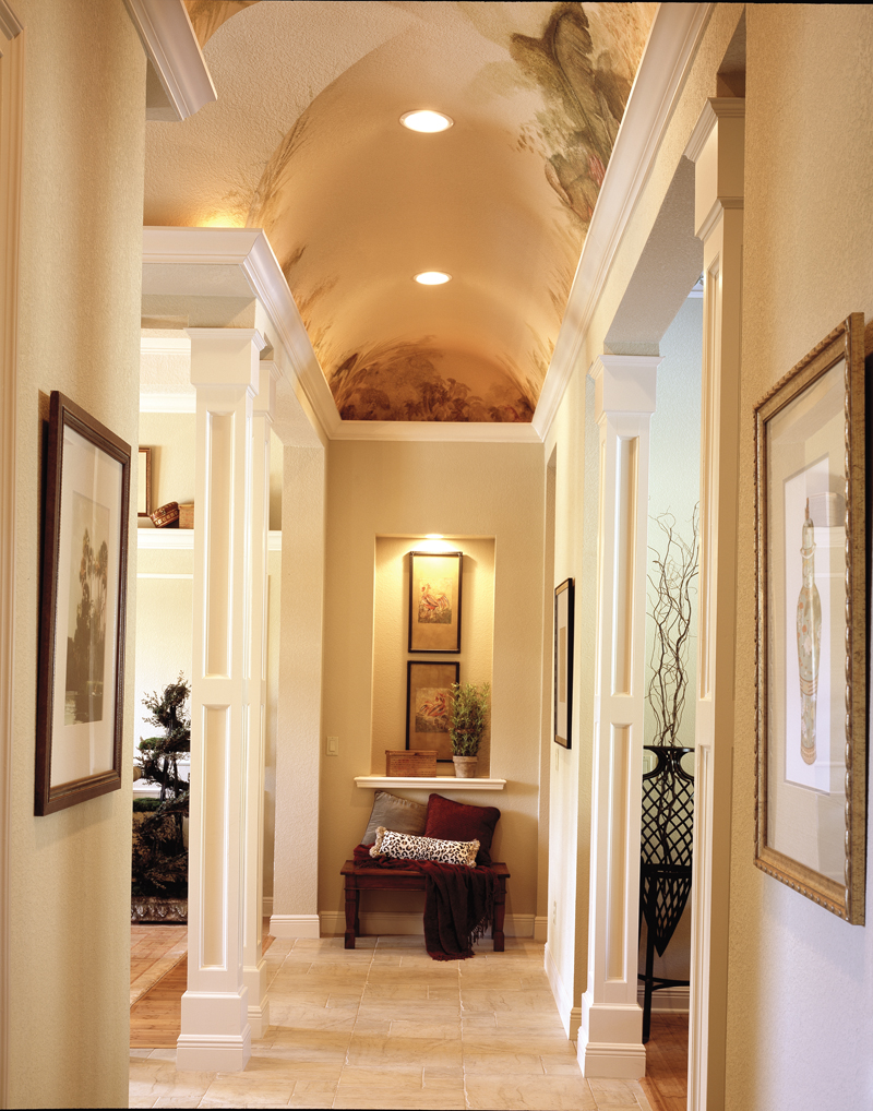 Illuminated hallway with dramatic columns and painted mural on the ceiling.